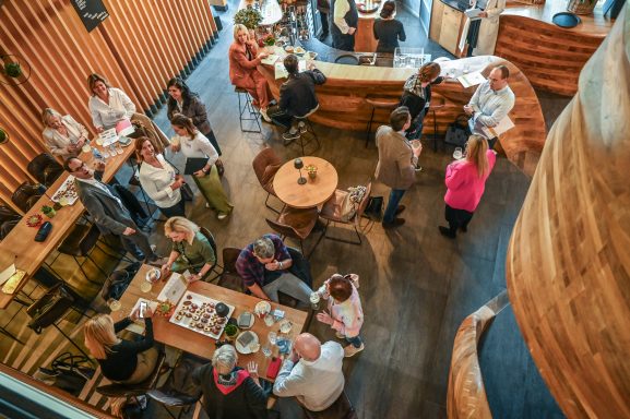 Belebte Café-Atmosphäre mit Teilnehmer:innen des 1. SCC Think Tank “Rethink Spa” an Tischen und Stehplätzen.